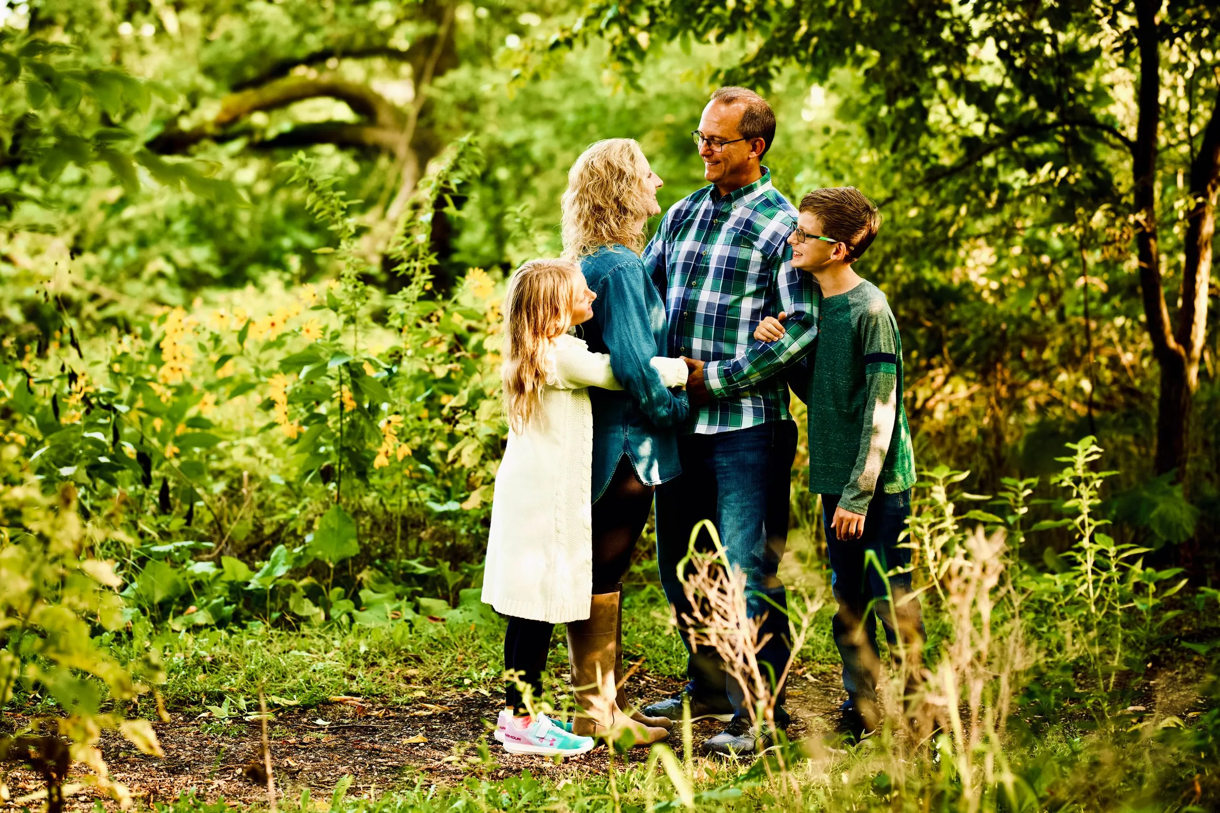 Family of four embracing on a wooded path