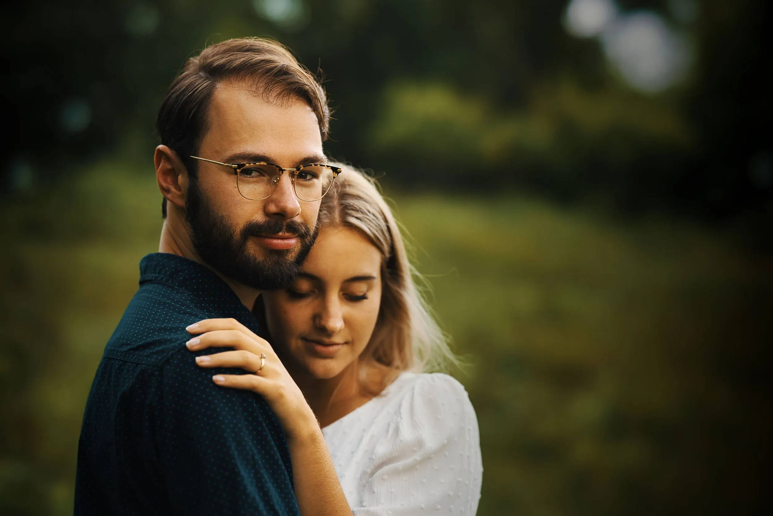 Engaged couple embracing in a green field